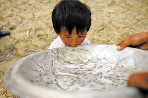 3月17日，云南广南县珠琳镇泥么冲村，一名村民用锅盖喂小孩喝水 记者 曲鸣飞/摄