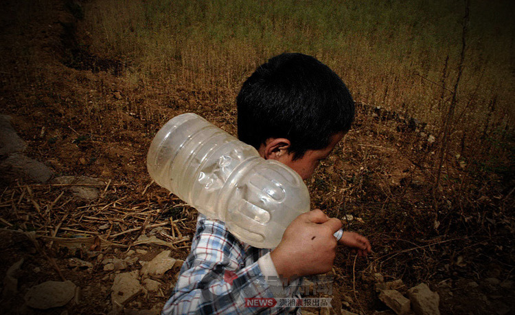 小男孩申金正将从远处辛苦打来的一小壶水扛回家。