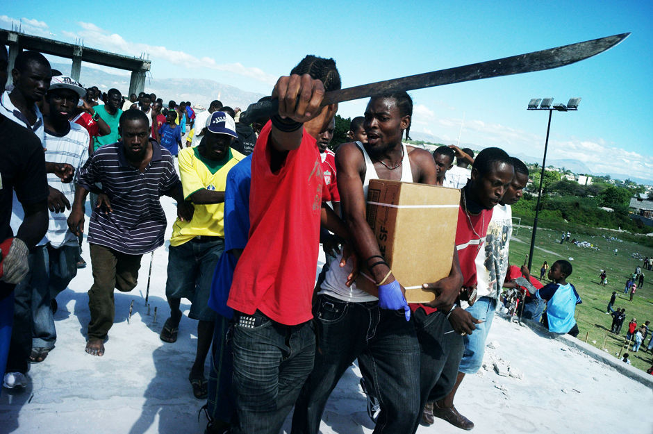 当地时间1月16日，海地首都太子港，一伙当地民众抢夺来此美军空投的食品，并持刀护送。