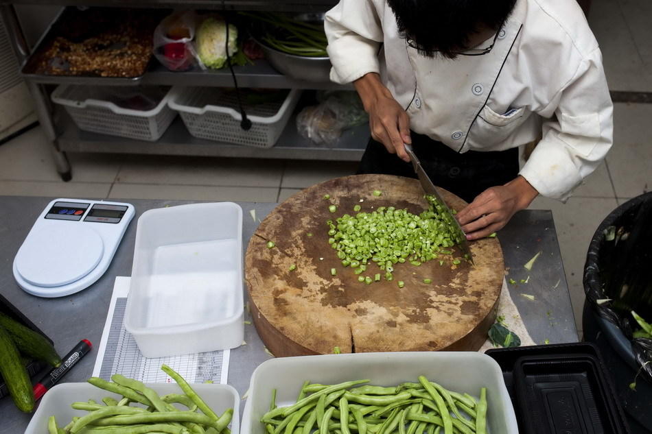 7月29日,砧板师傅王雷在后厨切菜.