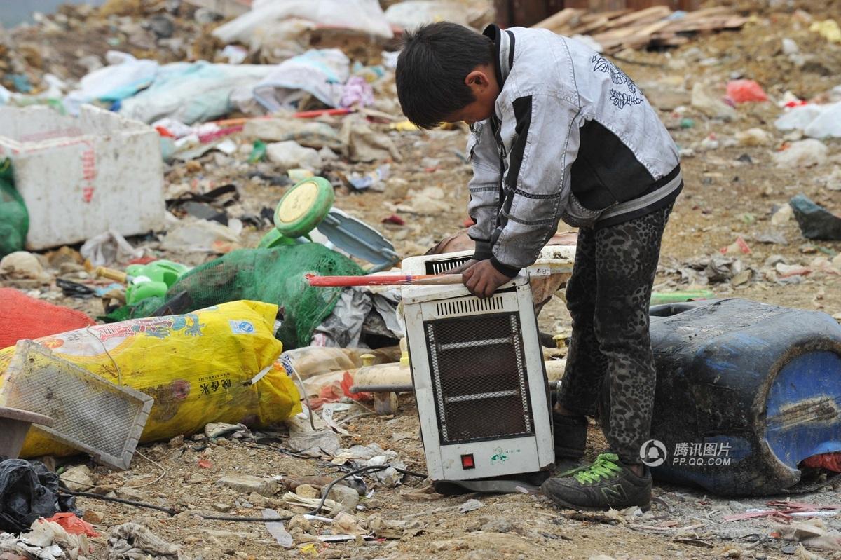 贵阳市花溪区一处大型垃圾填埋场,一名男孩躺在垃圾堆中吃着苹果