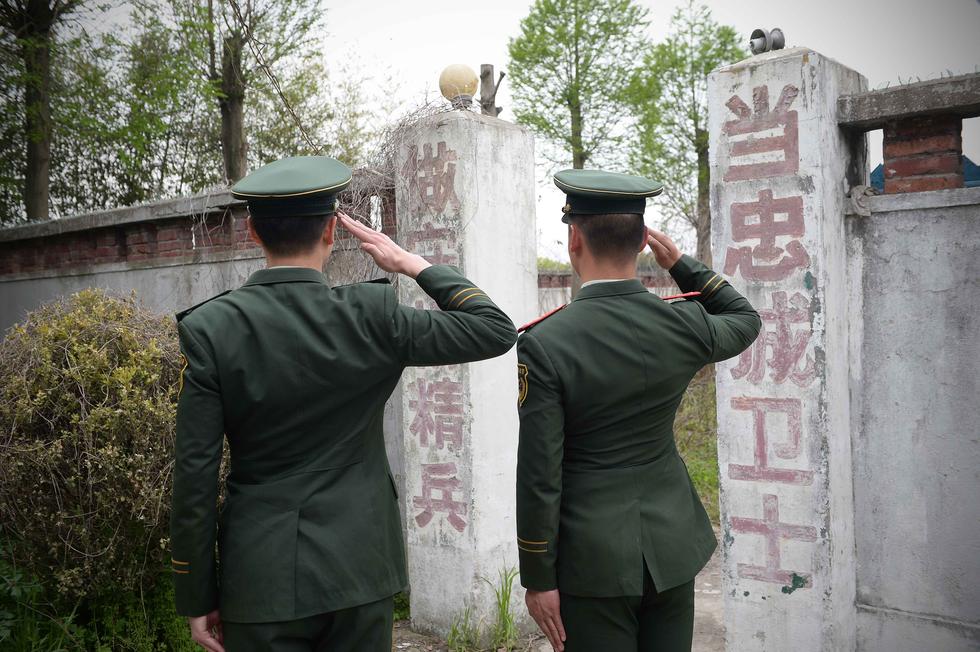 武警官兵站在曾经的哨所前敬礼.