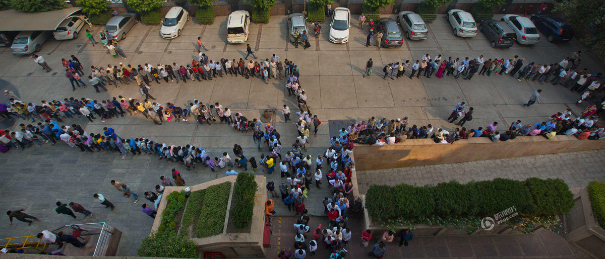 印度废钞乱象:警察手握棍棒维持排队秩序(组图)