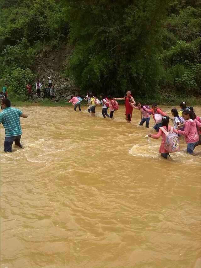 高清图—云南富宁县的那哈小学最美小学老师背学生过河上学