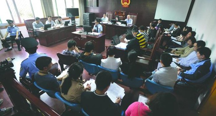 庭审现场,陈涛和两位代理律师坐在原告席上,对面坐着20多名被告