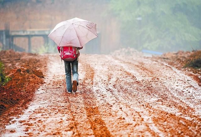 5月2日早晨,一场大雨后,邹章庭走在泥泞的上学路上.