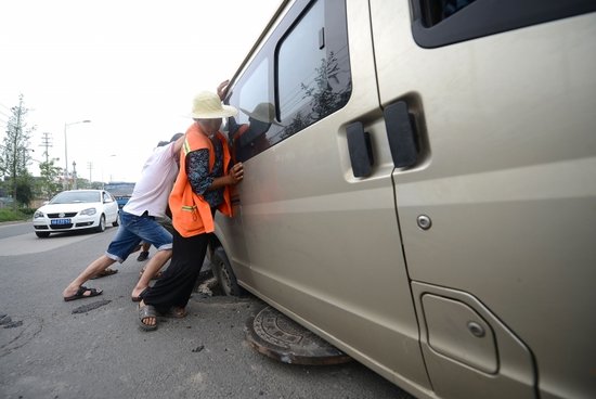 成都街头感人一幕:面包车被坑 路人合力推车
