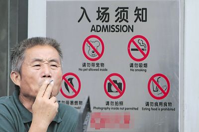 (图:市民在某商场门前吸烟,商场入场须知上有明显的禁烟标志.)