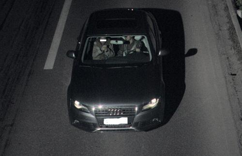 驾驶员夜间在高速路开车 扭头看副驾驶的手机