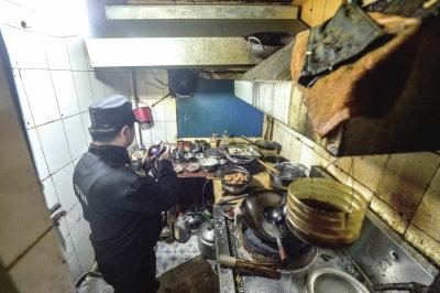 餐馆后厨油腻垃圾遍布灶台,工作人员正在拍照取证.