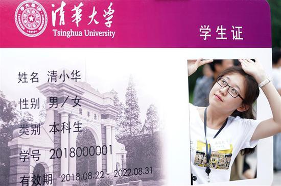 8月22日,在清华大学综合体育馆外,一名新生与"学生证"特色海报合影