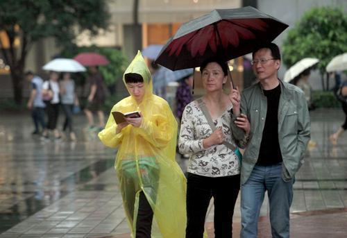 17日,解放碑,市民穿着雨衣打着伞逛街.重庆晨网记者 雷键 摄