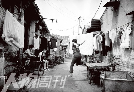2003年，北京宣武区培英胡同东口对面小巷，晾完衣服从三轮车上跳下的妇女