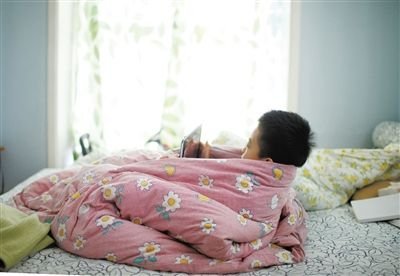 一名5岁的小男孩儿裹着被子用ipad玩游戏.新京报记者 韩萌 摄