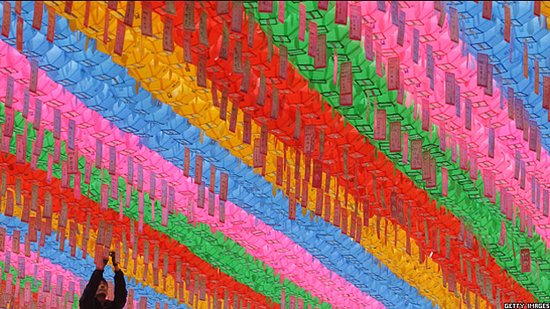 A Buddhist hangs colourful lanterns