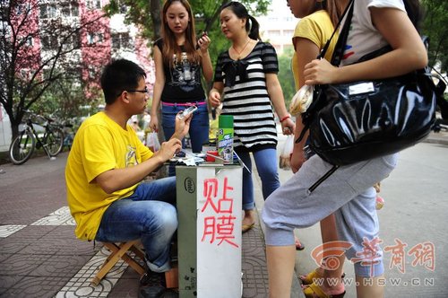 陈墨用在校园内摆摊贴膜,修手机,其手艺高超令他的生意不断.