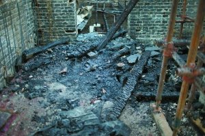 几根燃烧过半的木梁搭在砖墙上。