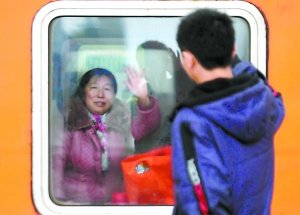 江西九江火车站站台,一位母亲隔着车窗向前来送行的孩子挥手告别.