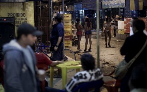 在巴西里约热内卢的维拉港含羞草红灯区;嫖客们坐在酒吧里,路边的妓女