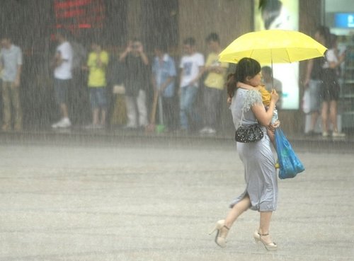 一市民抱着孩子打伞行走在雨中