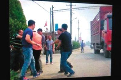 记者（粉色衣服者）遭多名男子抢夺相机。据人民网