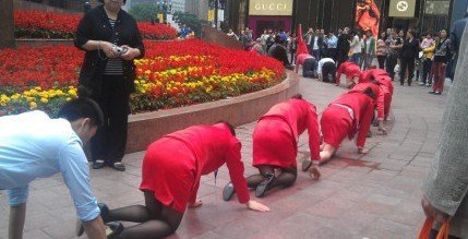 重庆一公司员工跪着绕解放碑爬行.图片来自网络