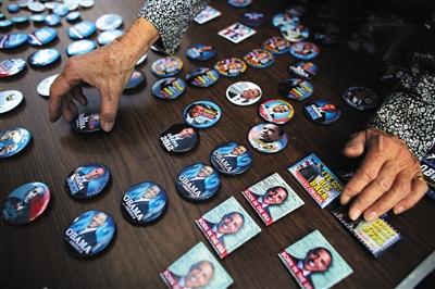 2012年10月，美国纽约曼哈顿，竞选人员展示印有奥巴马的纽扣。竞选团队在招募志愿者、推销候选人时常赠送小礼品，这也是一笔不可小觑的竞选费用。