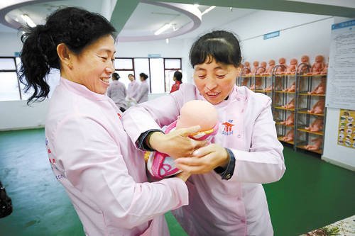 "月嫂"正在用婴儿模型培训抱婴儿的正确方法