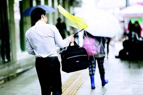 图为:昨日,武汉街头,大风使人无法撑起雨伞.