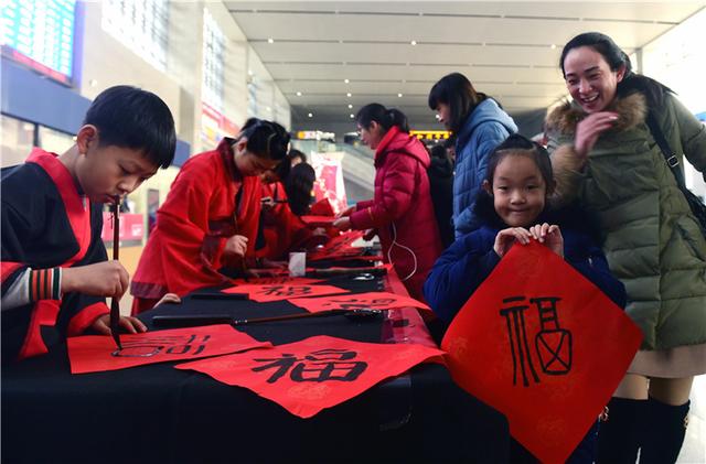 1月29日,小学生在沧州西站候车厅为旅客书写"福"字.