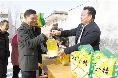 2月11日,湛河区曹镇乡吉村村民苏振杰(右)在给流转户发放慰问品.