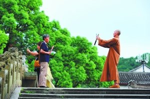 7月5日,一名僧人在普陀山法雨寺景区为游客拍照. cfp 图