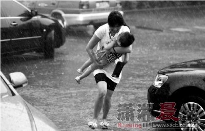 9月2日下午,株洲长江路,暴雨骤降,一名市民抱着孩子冲进超市避雨。 图/摄友团刘志慧