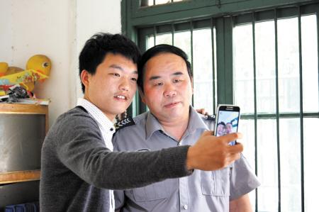 居住在学校宿舍六区的男生手举相机与保安"莫言大叔"合影.李一凡 摄