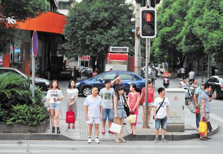 昨日下午,在晚报大道一人行横道旁,市民朋友顶着烈日等绿灯过马路.
