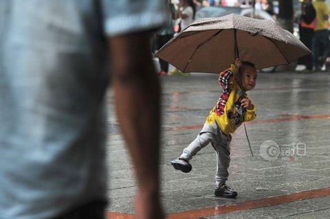 9月3日株洲芦淞市场一位小男孩打着雨伞在雨中跳舞。