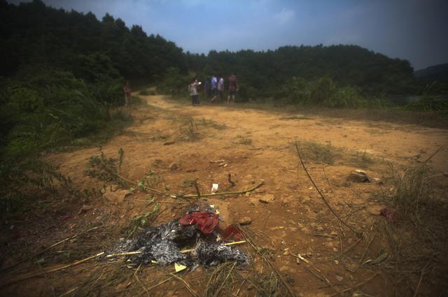 长沙岳麓区干子村,校车落水水库旁的地上残存着村民烧过的香烛纸钱