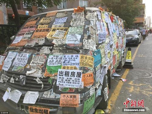 资料图：一辆大马路边的废旧汽车上被贴满了各式各样的房屋租售小广告。图片来源：视觉中国