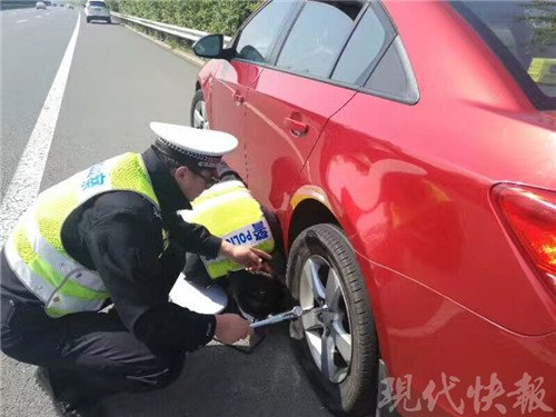 一家三口自驾游高速上遇爆胎 交警当起修车工