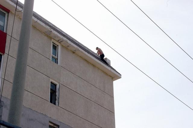 半裸男子骑在楼顶边缘欲轻生