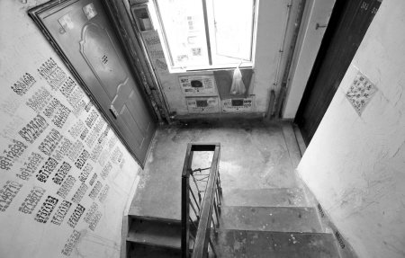 石小区陶家巷11号楼道墙上贴满小广告,居民老徐无奈在自家门口贴纸条
