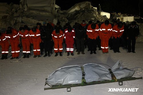 1月16日,在海地太子港,中国国际救援队队员以及公安部,外交部的工作人员在联合国驻海地稳定特派团倒塌大楼现场为挖掘出的一名中方失踪人员默哀.新华社记者 袁满 摄