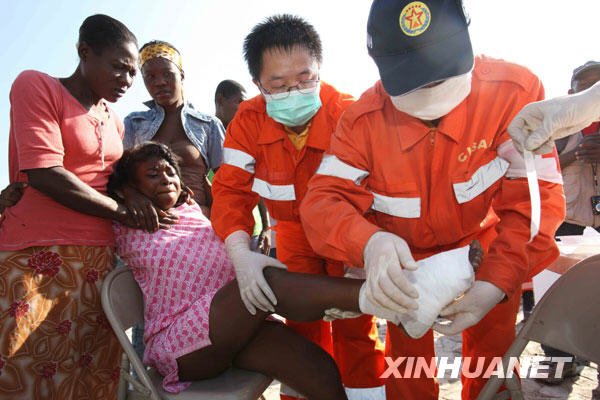 1月18日，中国国际救援队医生在海地首都太子港总统府广场前为一名受伤的女孩包扎伤口。新华社记者袁满摄
