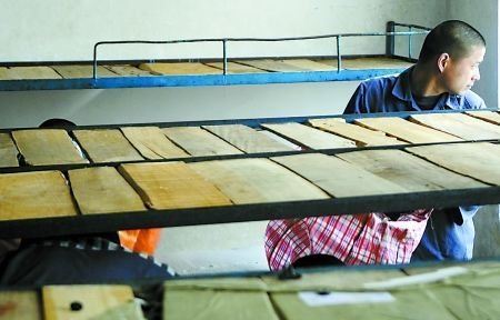 床铺已收拾干净，在押人员提着行李望着窗外 