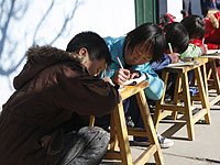 甘肃榆中孩子室外写作业晒太阳取暖