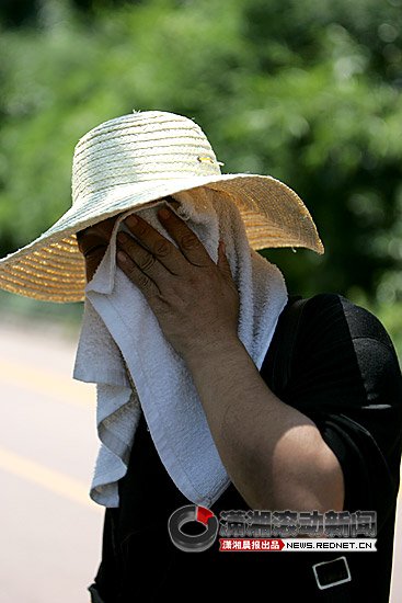 (近日,韶山南路,一位头戴草帽正在等车的乘客用毛巾擦. .