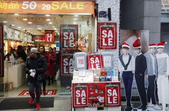 2015年12月19日,在韩国首尔,人们从一家打折的化妆品商店里走出。新华社记者