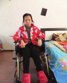 陈庆霞坐在轮椅上。她现在下身瘫痪，疾病缠身，生活不能自理。