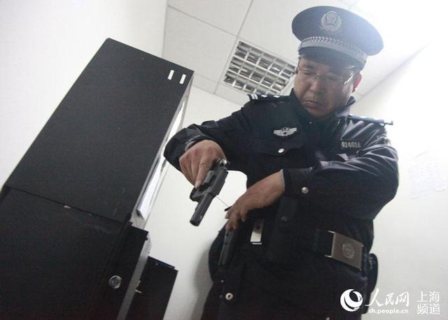 图为20日上午7时,上海市公安局长宁区江苏路派出所民警张令合正在验枪