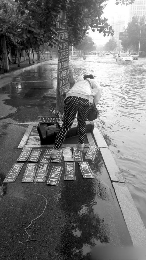 沈阳暴雨后 有人水中捞车牌百元一块不还价